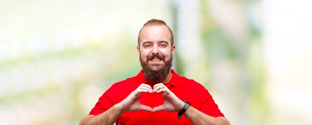 Mann mit roten shirt formt ein Herz mit seinen Händen