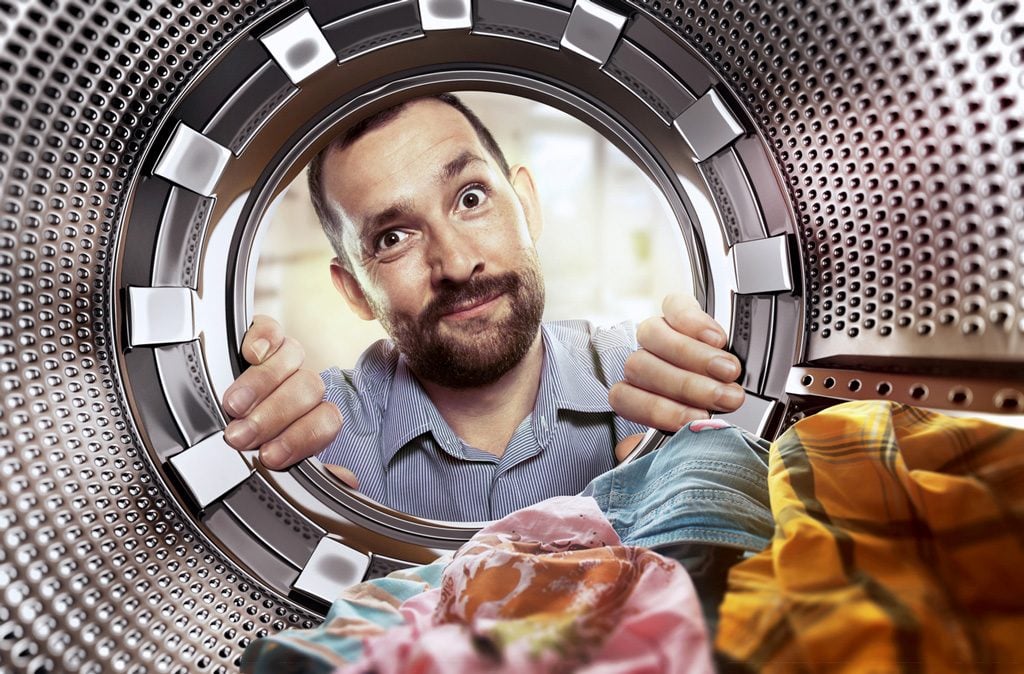 Mann schaut in eine Wäschetrommel