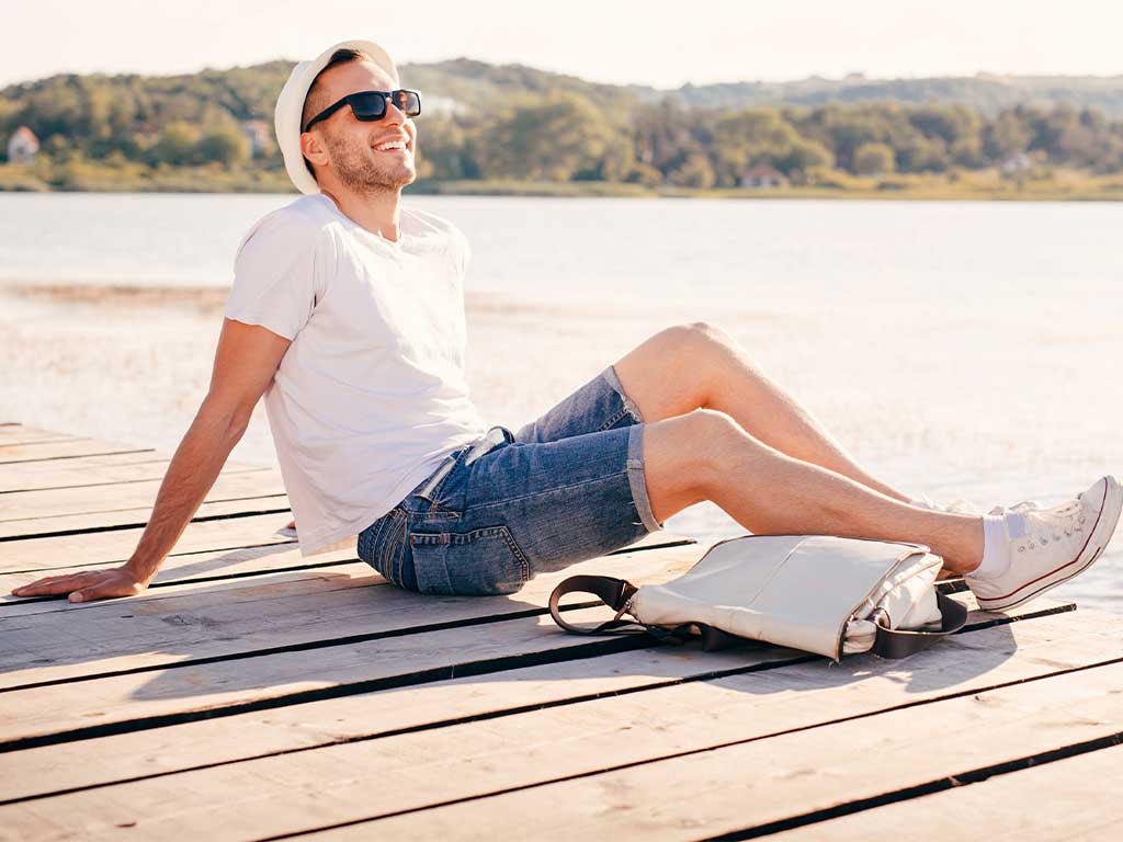 Mann sitz mit Hut am See
