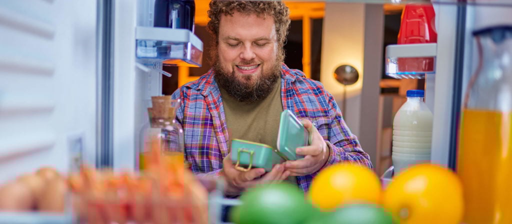 Mann mit Bart schaut in den Kühlschrank
