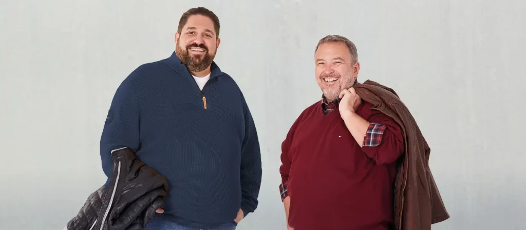 Zwei Männer in Kaschmirpullovern, jeder hält eine Jacke in der Hand.