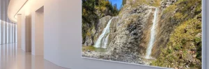 Moderner, heller Museumsgang mit weißen Wänden und Bildern an den Seiten.