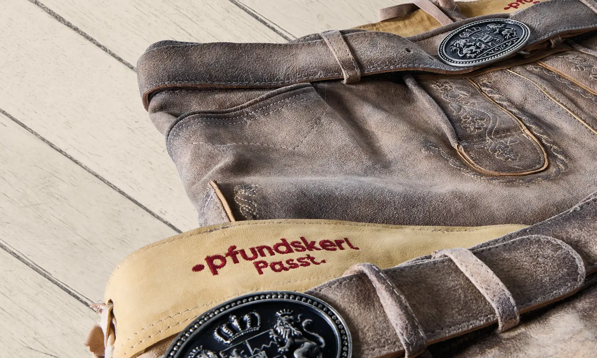 Zwei helle Lederhosen mit besticktem „Pfundskerl Passt“-Bund