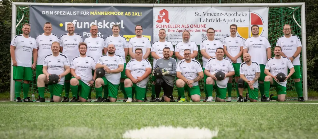 Mannschaftsfoto der Mendener Pfundskerle in weißen Trikots vor Sponsorwand