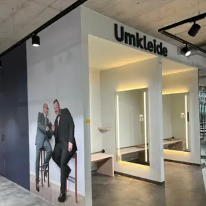 Blick auf die modernen Umkleidekabinen im Pfundskerl Megastore mit großem Wandbild zweier sympathischer Männer in Anzügen