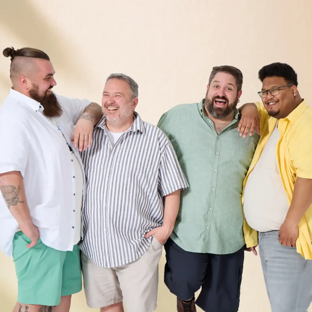 Vier Männer in großen Größen lachen gemeinsam – echte Pfundskerl-Models in sommerlicher Herrenmode ab 3XL.