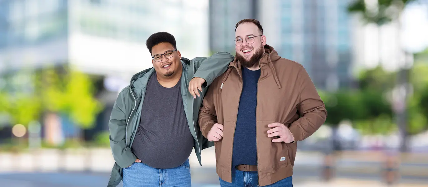 Zwei Männer mit Format tragen bequeme Übergangsjacken in großen Größen in urbaner Umgebung