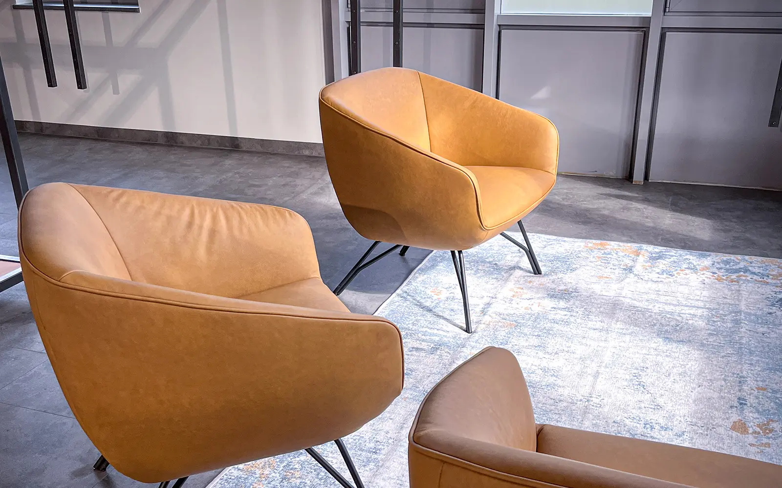Drei moderne, cognacfarbene Lounge-Sessel auf einem Teppich – stilvolle Sitzecke im neuen Pfundskerl-Store