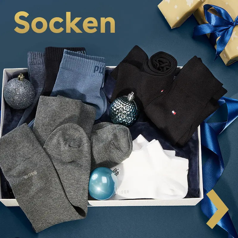 Verschiedene Herrensocken in neutralen Farben dekoriert mit Weihnachtskugeln.