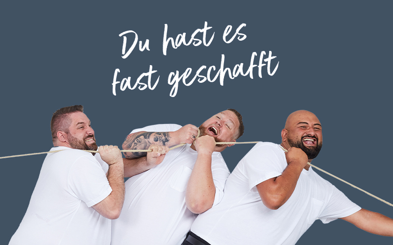 Drei Männer im T-Shirt ziehen gemeinsam an einem Seil – humorvoller Hinweis auf den letzten Anmeldeschritt