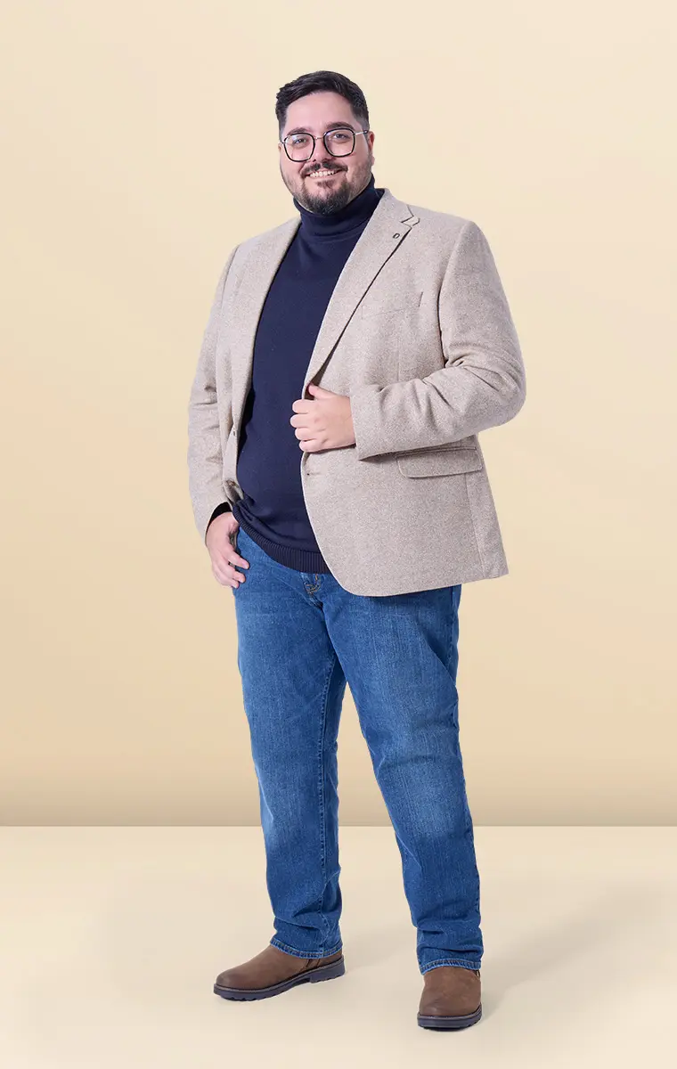 Mann im beigen Sakko und dunkelblauem Rolli mit Jeans – moderner Businesslook für große