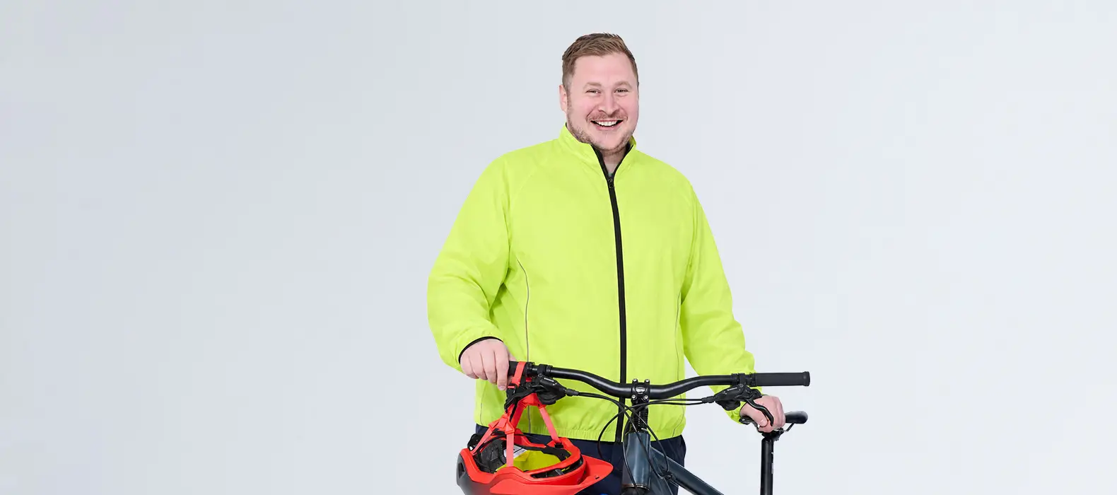 Lächelnder Mann in neongelber Fahrradjacke am Bike, sportlicher Radsportlook in großen Größen