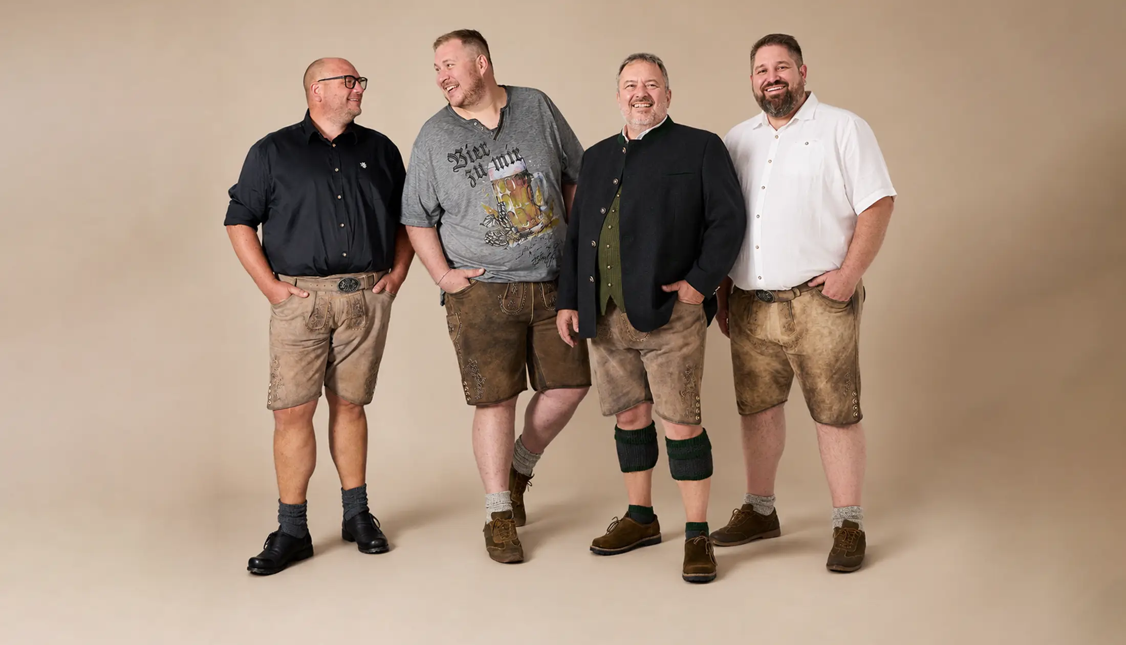 Vier Männer in Lederhosen und Trachtenlooks präsentieren bequeme Trachtenmode in großen Größen