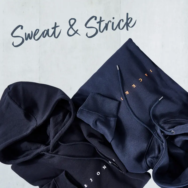 Dunkelblaue Kapuzenpullover von Jack & Jones locker arrangiert vor Betonwand – moderne Sweats für Männer mit Format.