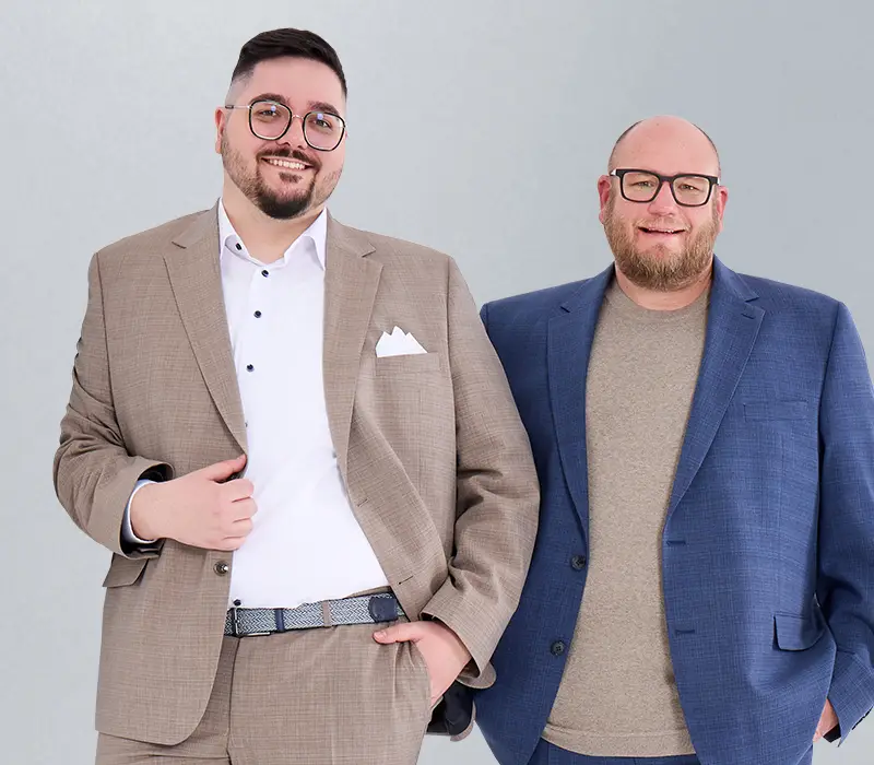 Nahaufnahme zweier lächelnder Männer in großen Größen – Sakko-Outfits für festliche und geschäftliche Anlässe bei Pfundskerl