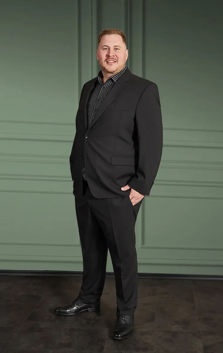 Mann in großer Größe im schwarzen Anzug vor grünem Wandpanel