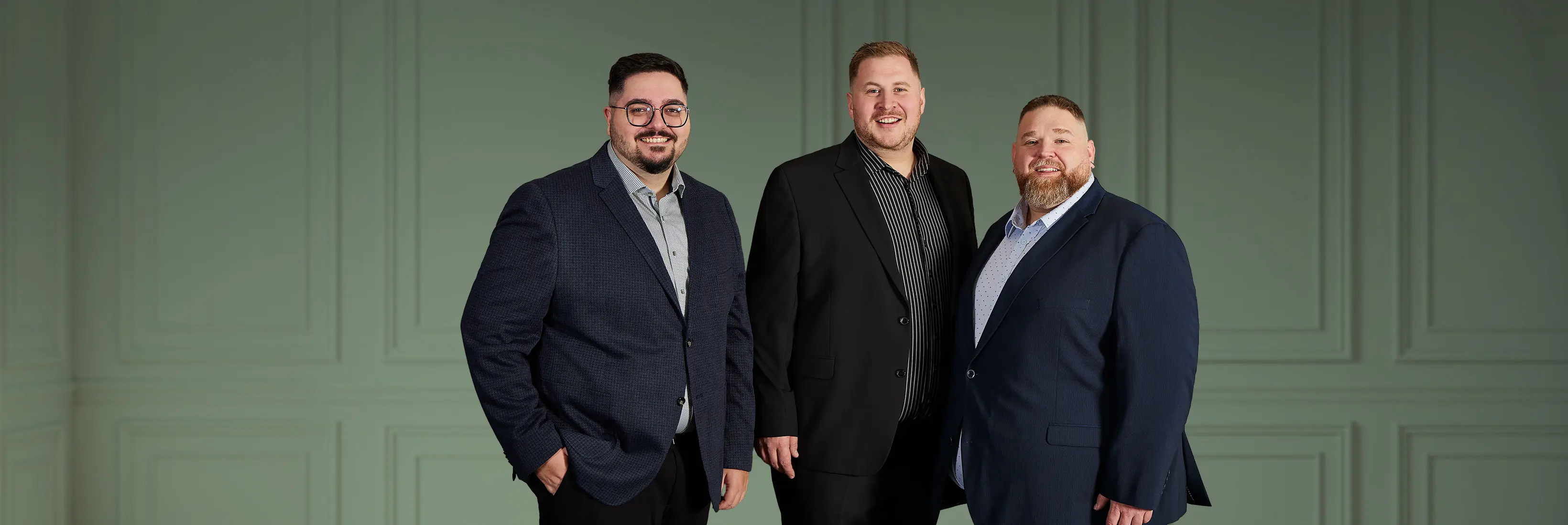 Drei Männer in chicen Festtagsanzügen vor edlem Hintergrund