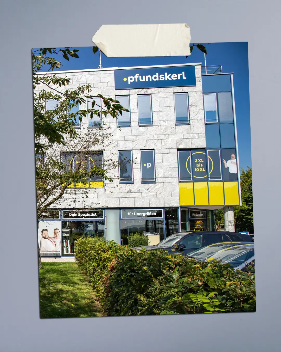 Außenansicht des Pfundskerl Erlebnis-Stores in Neufahrn mit Pfundskerl Logo und Herrenmode in großen Größen.