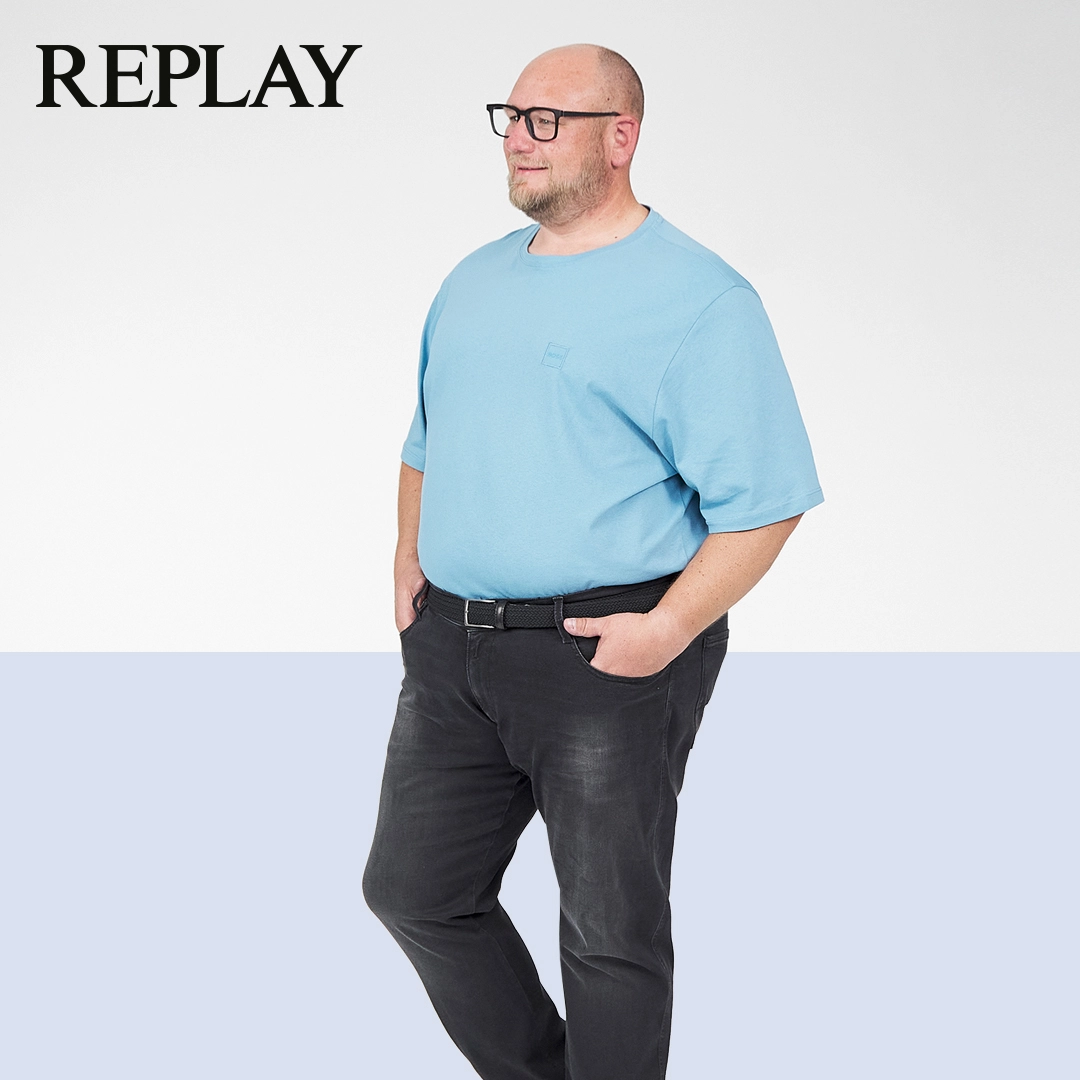 Mann mit schwarzer Replay Jeans in großen Größen – modern kombiniert mit blauem Shirt
