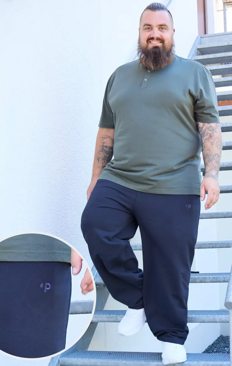 Lässig gestylter Pfundskerl in olivgrünem Shirt und dunkelblauer Hose mit Logodetail