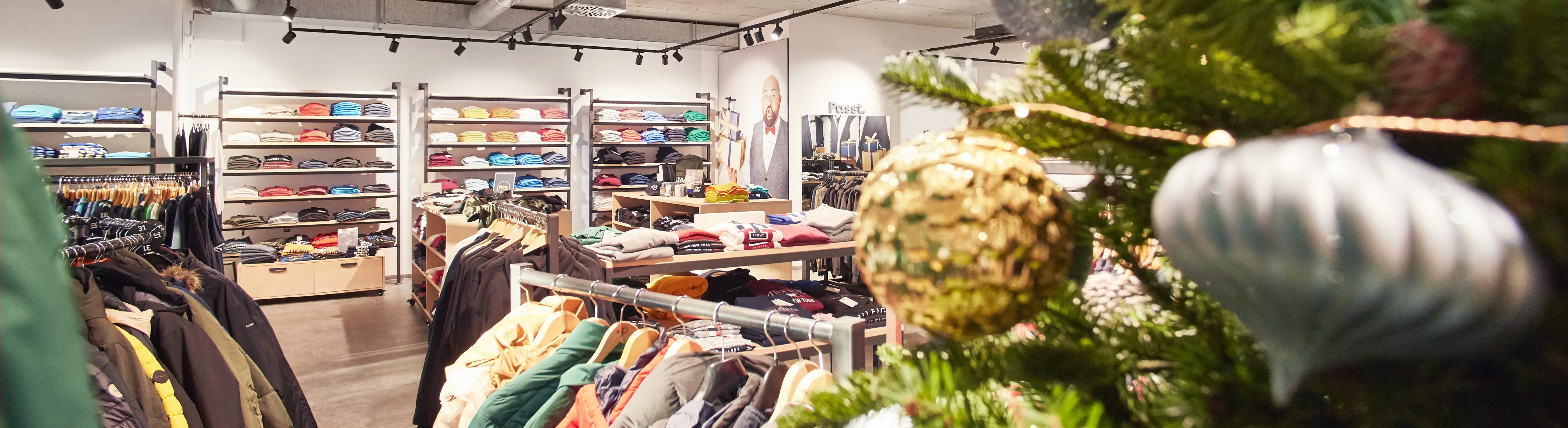 Blick über Verkaufsfläche mit Mode in großen Größen – mit Weihnachtsdeko im Vordergrund