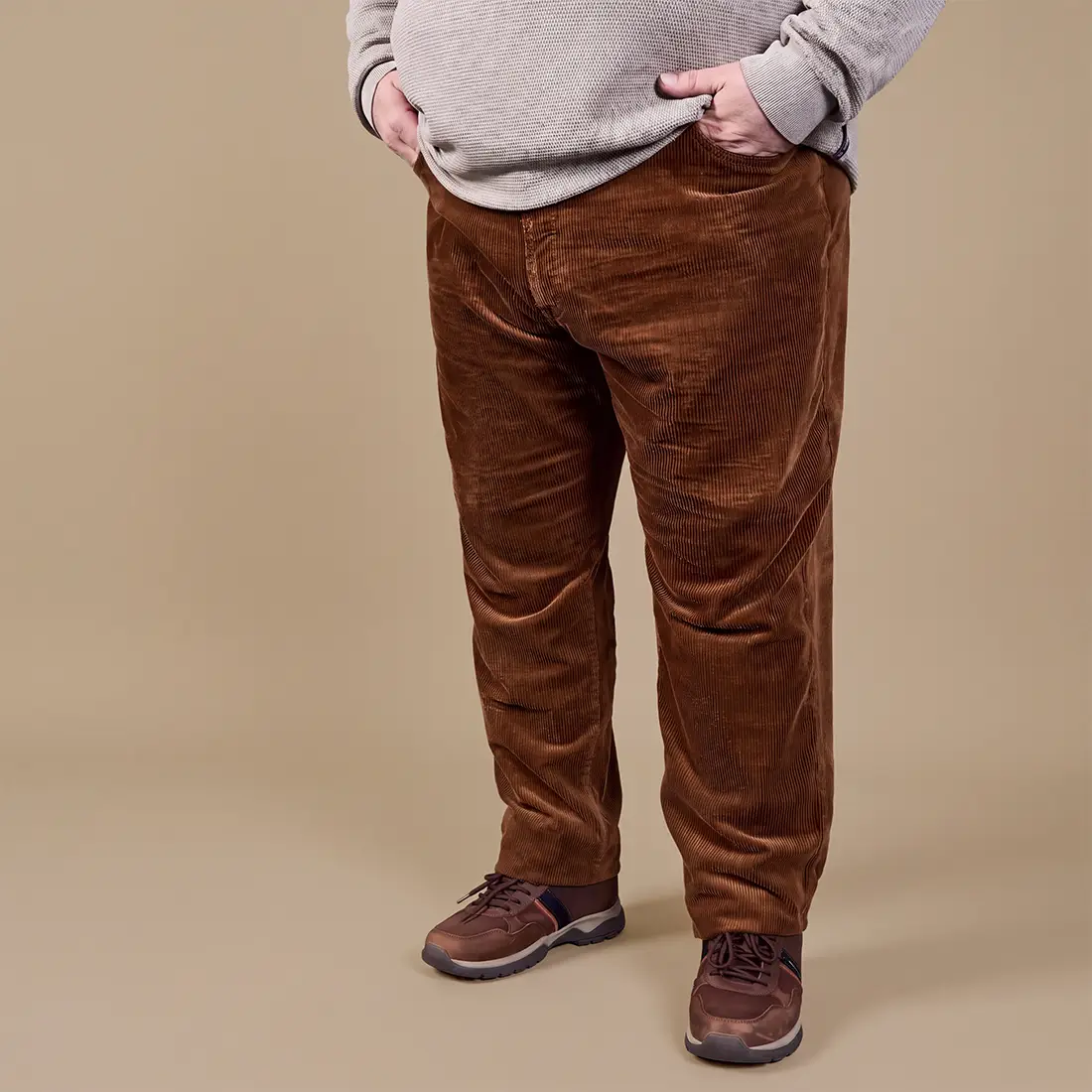 Braune Cordhose für Herren in großer Größe kombiniert mit hellem Pullover und braunen Freizeitschuhen.
