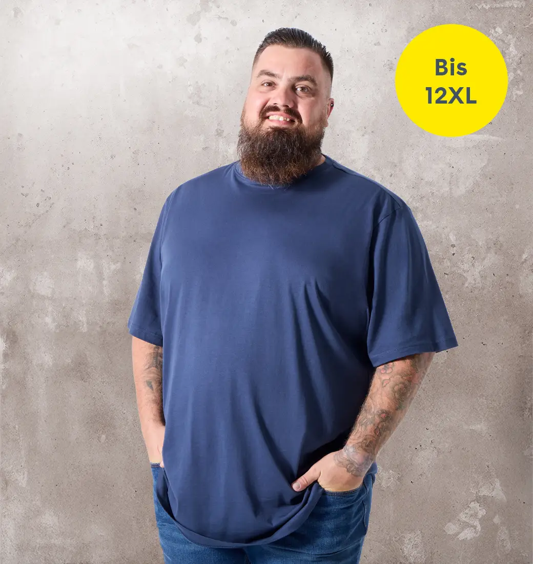 Mann mit Bart trägt ein dunkelblaues T-Shirt und Jeans vor hellem Betonhintergrund mit Hinweis bis 12XL