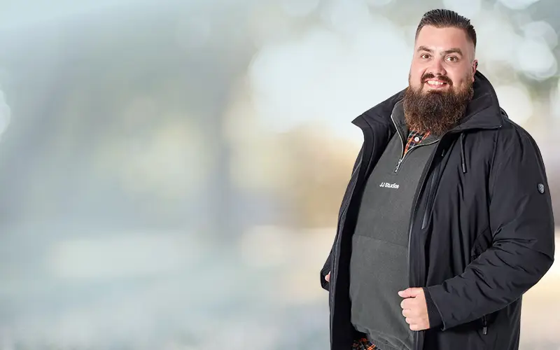 Mann mit schwarzer Outdoorjacke und wetterfestem Look für große Größen