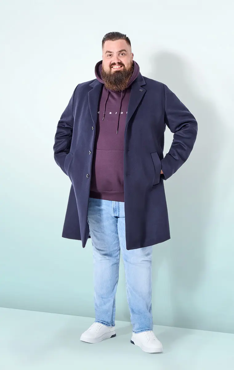 Mann im Hoodie unter dem Mantel mit heller Jeans – eleganter Office-Style für den Alltag