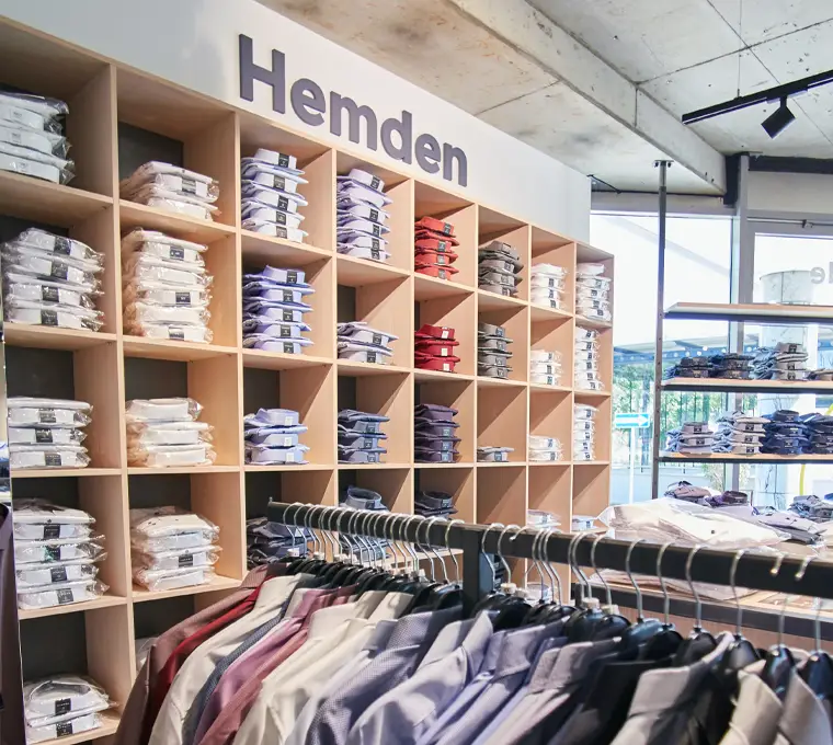 Regalwand voller hochwertiger Hemden in Übergrößen, ordentlich gefaltet und sortiert – mit zusätzlicher Stange für hängende Modelle
