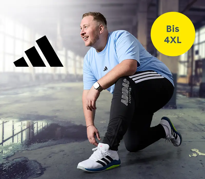 Mann in großer Größe kniet im Fitnessstudio und trägt adidas Trainingsanzug und Sneaker – Sportbekleidung bis 4XL