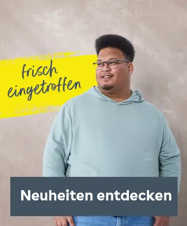 Mann mit Brille trägt einen hellen Hoodie und Jeans und steht locker vor hellem Studiohintergrund