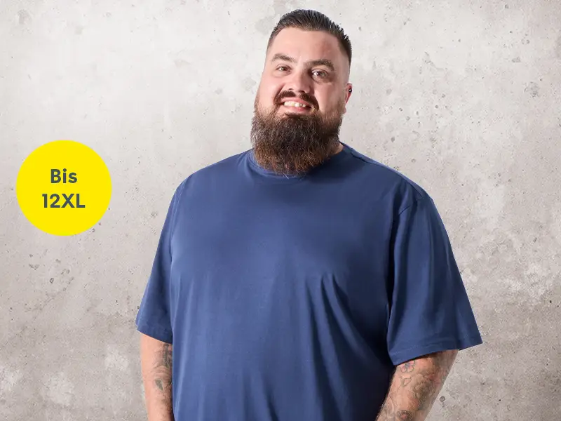 Mann in dunkelblauem T-Shirt mit Händen in den Hosentaschen vor neutralem Hintergrund mit Größenhinweis bis 12XL